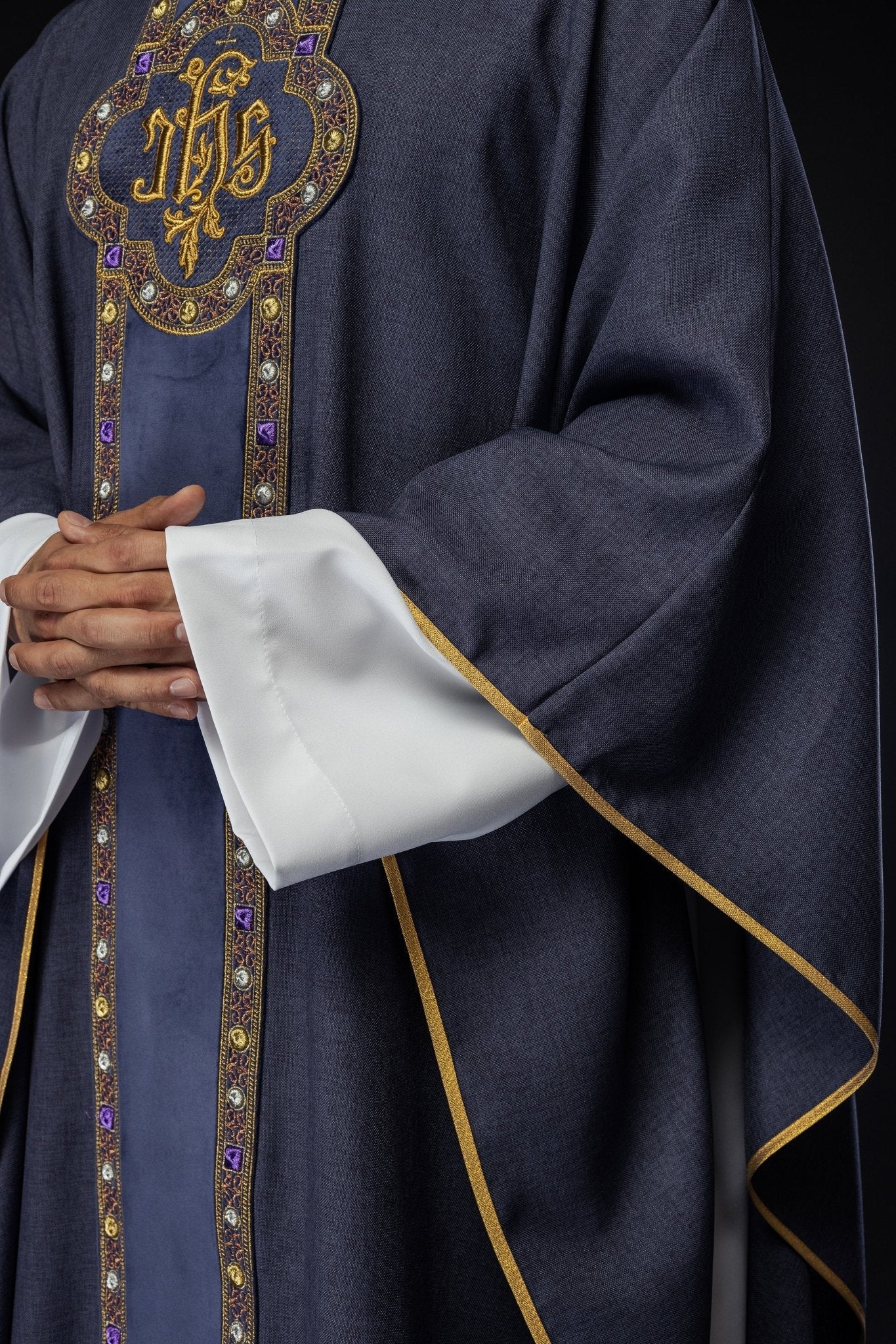 Ornat z bogato haftowanym pasem i lamówką wokół haftu IHS i kołnierza w kolorze fioletowym